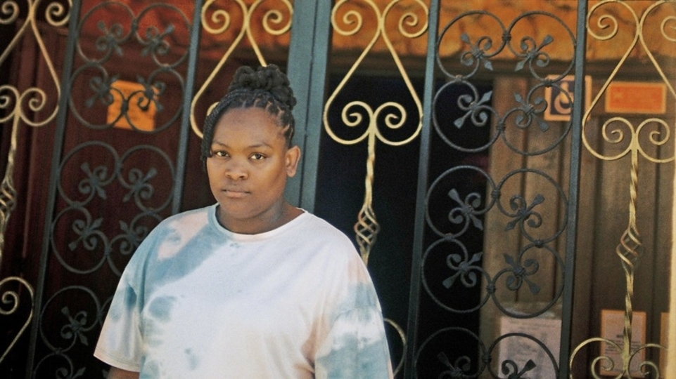 Photo of Nídia wearing a tie-dye jumper with her hair in braids