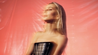 Photo of KASIA wearing a leather top and posing in front of an orange backdrop