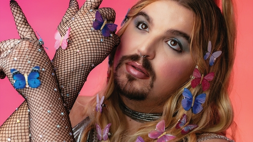 Close up shot of Wreckno with fishnet gloves and colourful butterflies in their hair