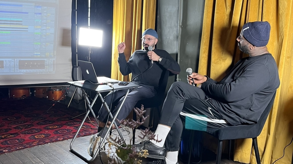 Photo of Moving Still and Tony Nwachukwu recording a workshop in front of a yellow curtain