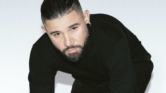 Photo of Skrillex wearing a black turtleneck jumper in front of a white background