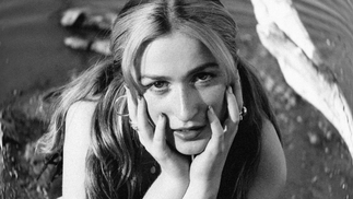 Black and white photo of Imogen resting her head on her hands and lying on the floor