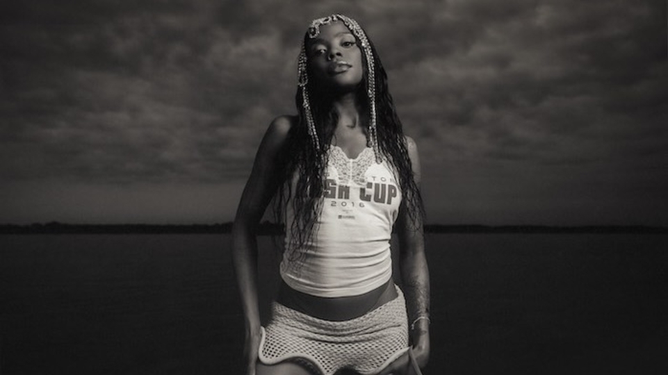 Photo of BAMBII posing in front of a beach in black and white