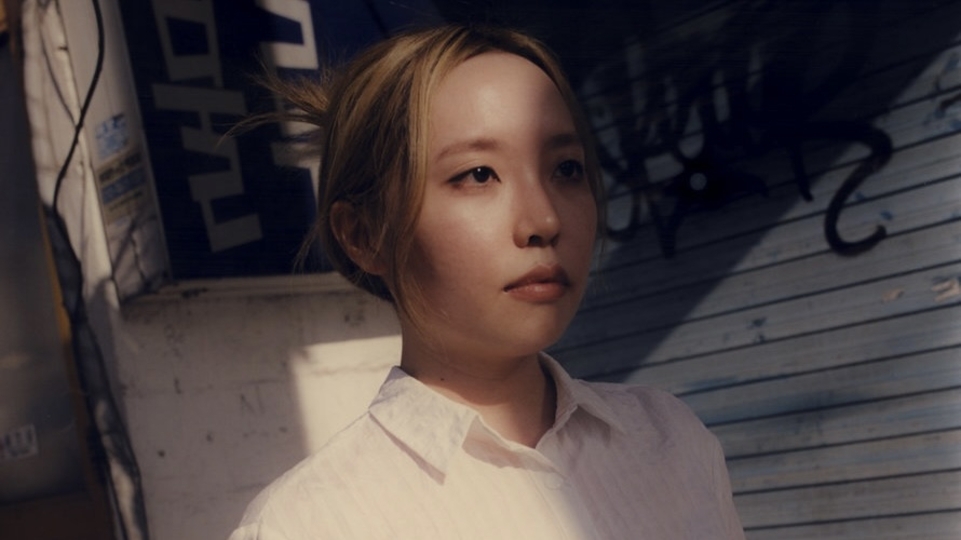 Photo of Closet Yi wearing a white shirt in front of an industrial background