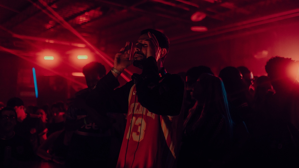 Hamdi performs live in a dark red club space