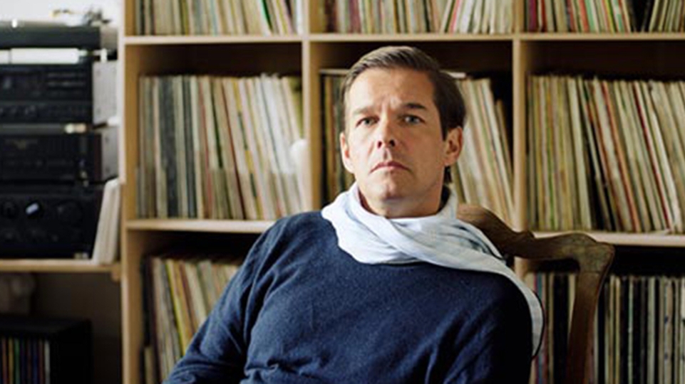 Moritz von Oswald poses in front of a bookcase of vinyl records