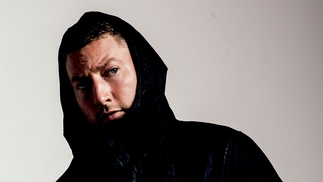 Photo of Azari posing wearing a black hoodie.