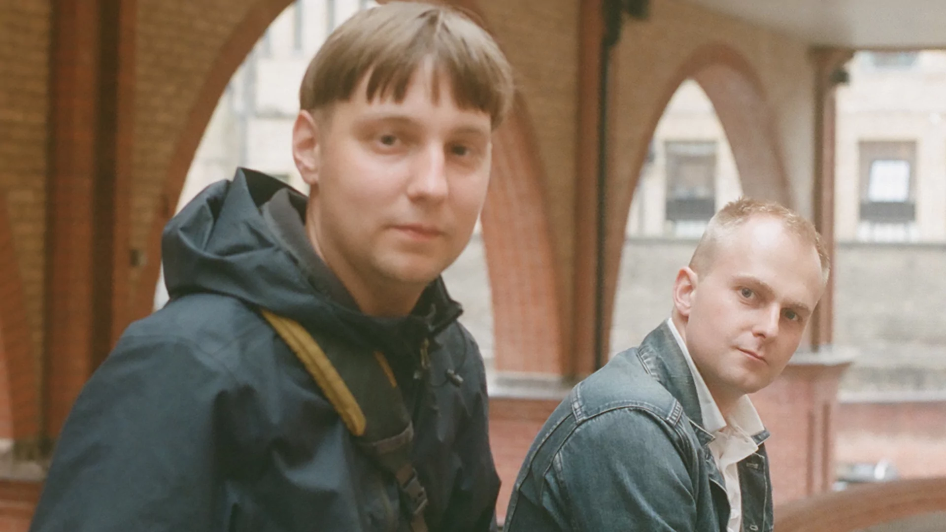 Photo of Simkin and DJ Pitch sitting on a red brick wall